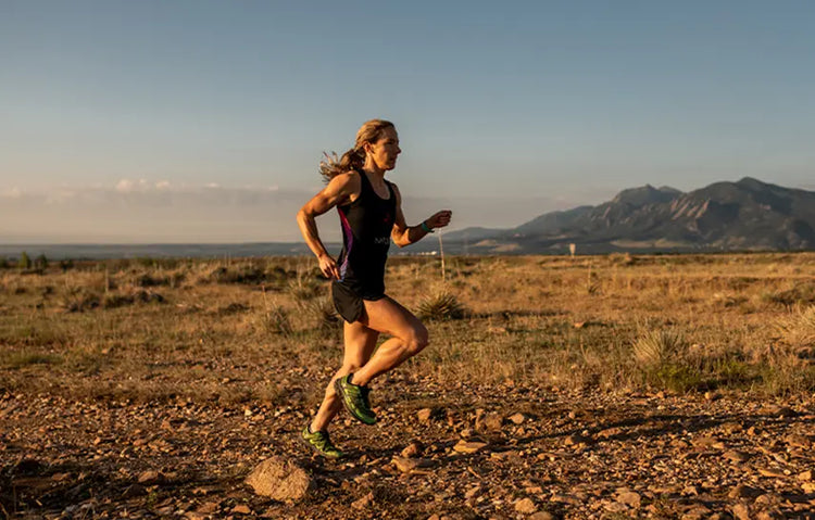 Rose Wetzel running on a rocky trail with mountains in the background